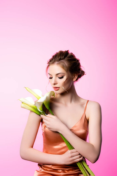 elegant beautiful blonde woman holding calla flowers isolated on pink - Foto, Bild