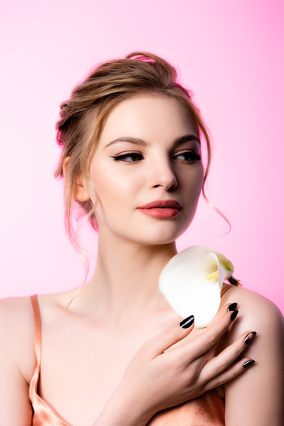elegant beautiful blonde woman holding calla flower on shoulder isolated on pink - Foto, Bild