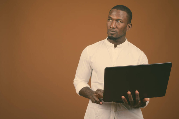 Студийный снимок красивого африканского бизнесмена в белой рубашке на коричневом фоне - Фото, изображение