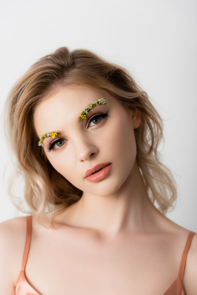 beautiful blonde woman with wildflowers on eyebrows looking at camera isolated on white - Fotoğraf, Görsel