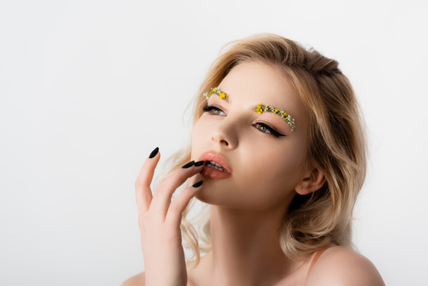 beautiful blonde woman with wildflowers on eyebrows touching lips isolated on white - Foto, imagen