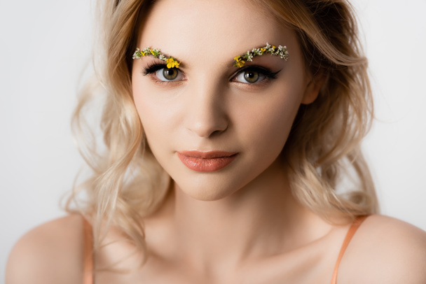 beautiful blonde woman with wildflowers on eyebrows isolated on white - Zdjęcie, obraz