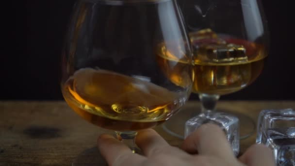 Imágenes en cámara lenta de coñac o whisky en un vaso, degustación de alcohol, copa de espíritus dorados en una mano
 - Metraje, vídeo
