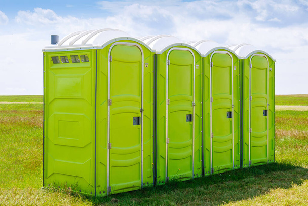 Portable toilet on the grass on a background of clouds. - Photo, Image