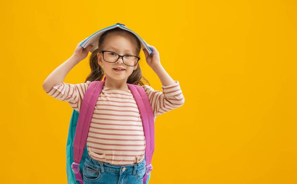Back to school and happy time! Cute industrious child on color paper wall background. Kid with backpack. Girl ready to study. - Φωτογραφία, εικόνα