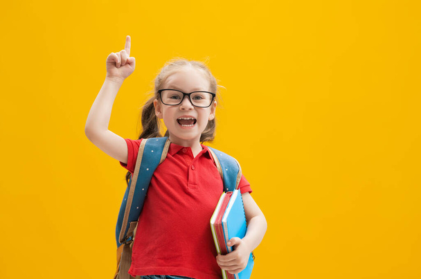 Back to school and happy time! Cute industrious child on color paper wall background. Kid with backpack. Girl ready to study. - Valokuva, kuva