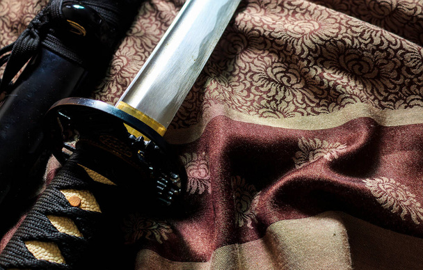 close-up japonais épée takana sur satin avec des couleurs chaudes automne, soft-focus en arrière-plan. sur la lumière - Photo, image