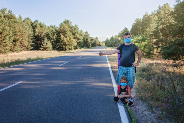 Yerel bir gezgin. Orta yaşlı bir baba, sırt çantalı ve sağlık maskesi takmış. Yerel tatillerinde yolda araba durduruyor. Yeni normal bir yaz tatili, açık hava yaşam tarzı. - Fotoğraf, Görsel