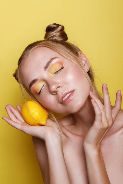 menina com maquiagem multicolorida e limão em um fundo amarelo brilhante
 - Foto, Imagem
