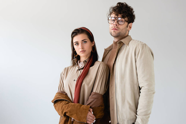 fashionable couple in autumn clothes looking at camera while posing isolated on grey - Photo, Image