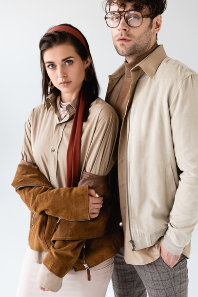 pareja de moda en ropa de otoño mirando a la cámara mientras posan en gris
 - Foto, Imagen