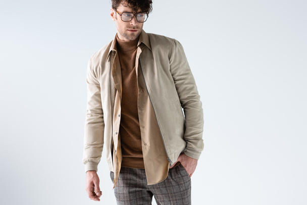 joven, hombre de moda en gafas con la mano en el bolsillo aislado en gris
 - Foto, Imagen