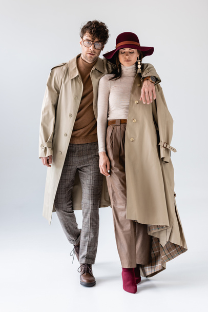 handsome man hugging stylish woman in hat while posing on grey - 写真・画像