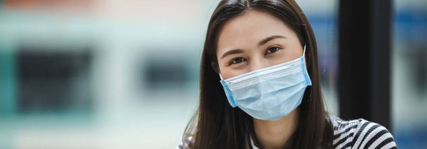 Aziatische vrouwen met een chirurgisch masker ter bescherming tegen ziekten en speekselinfecties in de lucht, tijdens de uitbraak van het Covid 19-virus of het Corona-virus, gezondheids- en zorgconcept. - Foto, afbeelding