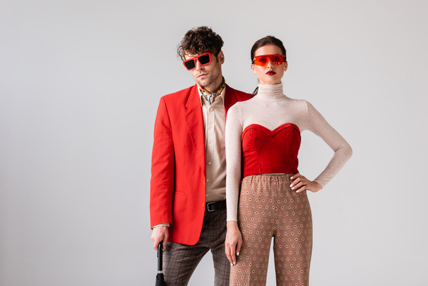 fashionable couple in sunglasses looking at camera isolated on grey - Photo, Image