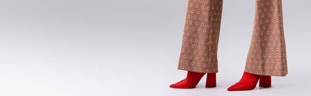 cropped view of stylish woman in beige trousers and red boots on grey, horizontal image - Foto, immagini