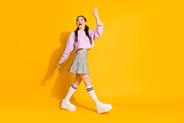 Full length profile side photo of excited energetic teen girl go walk say good bye to her family wear checkered stylish trendy sneakers isolated over bright color background - Foto, Imagem