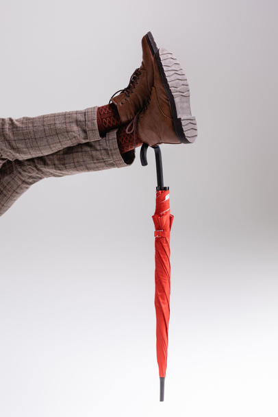 Vue partielle des jambes de l'homme appuyées sur le parapluie rouge sur le gris - Photo, image