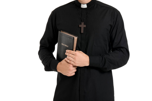 Handsome priest with Bible on white background - Фото, изображение