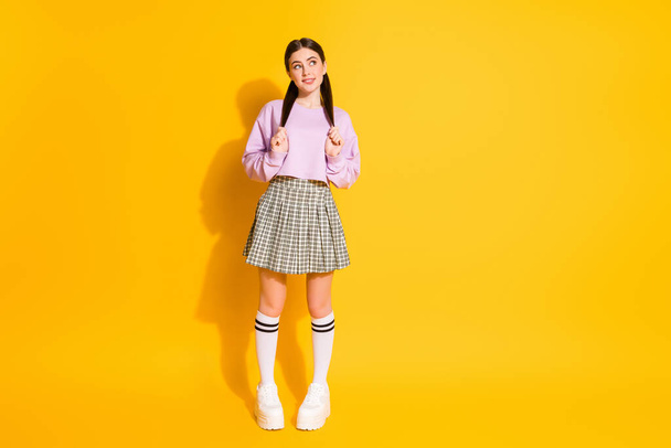 Full length body size view of her she nice attractive lovely pretty charming shy cheery girl posing thinking biting lip isolated on bright vivid shine vibrant yellow color background - 写真・画像
