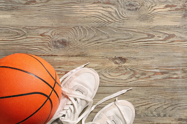Ball for playing basketball game with shoes on wooden background - Photo, Image