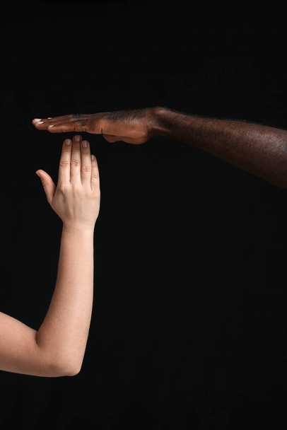Handen van blanke vrouw en Afro-Amerikaanse man op donkere achtergrond. Racisme - Foto, afbeelding
