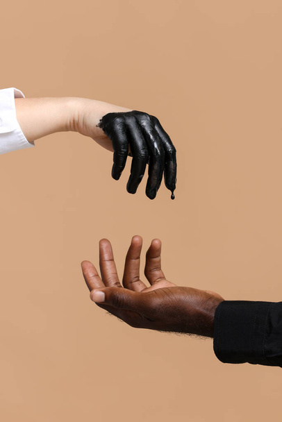 色の背景に白人女性とアフリカ系アメリカ人男性の手。人種主義の概念 - 写真・画像