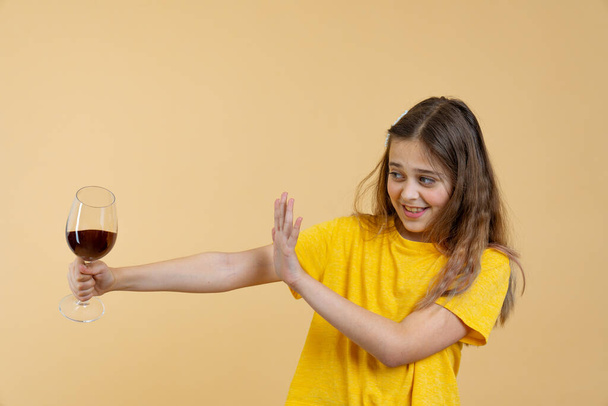 Μπρουνέτ έφηβος σε κίτρινο t-shirt με κρασί στο χέρι - Φωτογραφία, εικόνα
