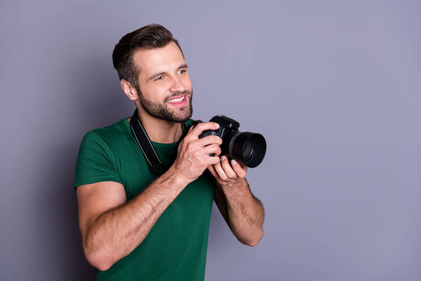 Profile side photo of cheerful guy enjoy summer rest weekend hold dslr camera want make photo look copyspace wear casual style clothes isolated over gray color background - Foto, Bild