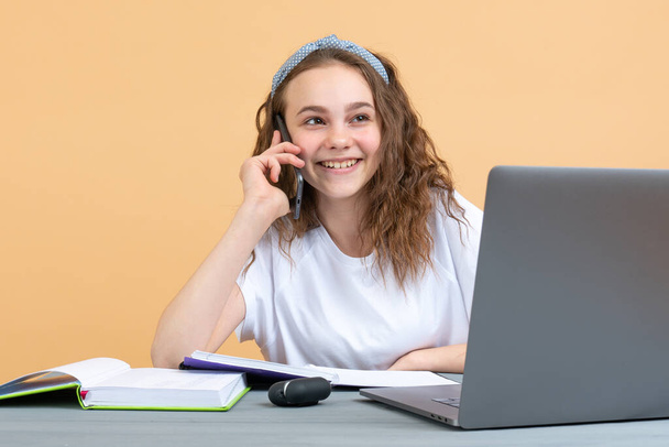 Glücklich lächelnde Studentinnen lernen zu Hause, während sie mit Laptop am Tisch sitzen und telefonieren - Foto, Bild