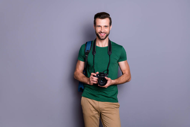 Portrait of cheerful guy ready travel abroad hold bag professional dlsr camera wear style stylish tendy clothes isolated over gray color background - Photo, image