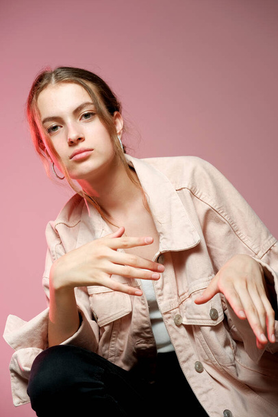 A girl in a pink denim shows different emotions and poses on a pink background. - Фото, изображение