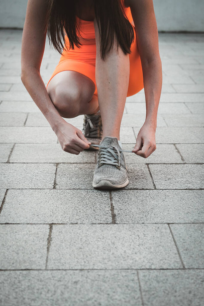 Крупним планом жіноче кросівки. Фітнес жінка зав'язує шнурки для взуття, спортивний бігун готовий до бігу на відкритому повітрі вранці
 - Фото, зображення