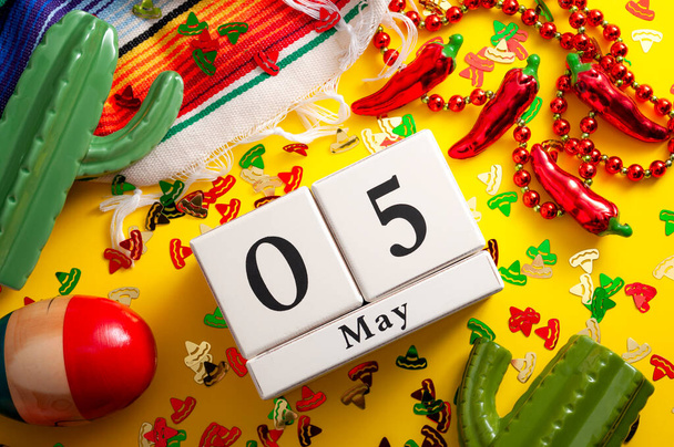 Meksikolainen fiesta ja Cinco de Mayo osapuolen käsite kalenteri asetettu 5. toukokuuta, jalapeno pippuri kaulakoru, maracas, kaktus ja perinteinen matto peitetty sombrero muotoinen konfetti keltaisella pohjalla - Valokuva, kuva