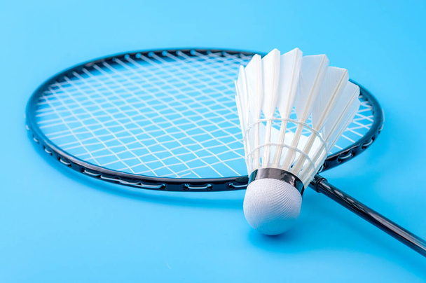 Competitive sports and high performance in tournament match conceptual idea with badminton rackets and shuttlecock (birdie) isolated on blue court background - Photo, Image
