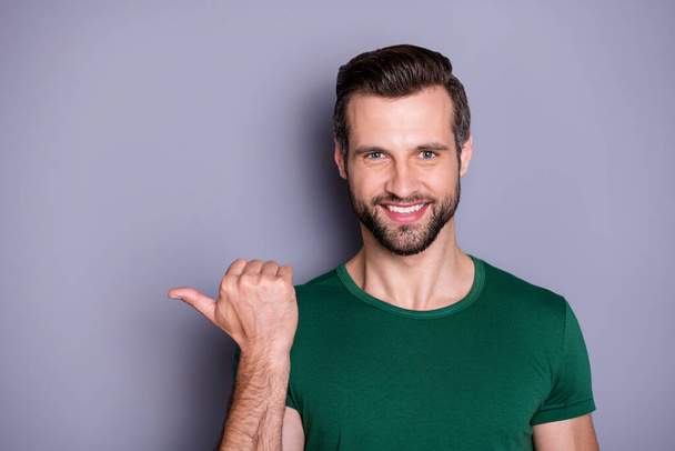 Cloeup photo of attractive handsome guy good mood direct thumb finger side empty space show cool offer shopping price wear casual green t-shirt isolated grey color background - Foto, imagen