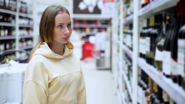 Woman chooses wine in the Supermarket, customer selects product on the shelves in the store. - Materiał filmowy, wideo