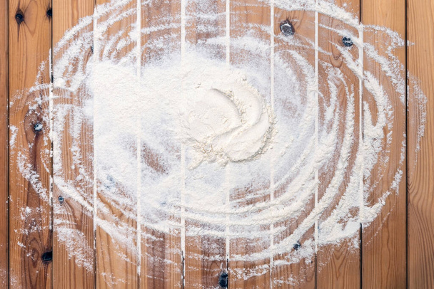 Flour scattered on the wooden table. Flour on the table surface. Baking  background  - Photo, image