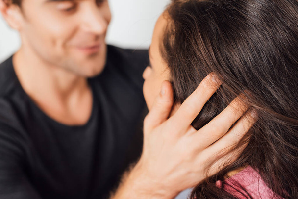 Selective focus of man touching hair of girlfriend isolated on grey  - Photo, Image