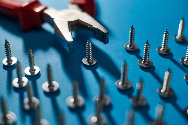 Screws and pliers on a blue background. - Foto, afbeelding