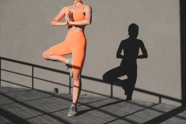 Yoga yapan genç bir kadın. Atletik vücut silueti, sağlıklı yaşam tarzı. - Fotoğraf, Görsel