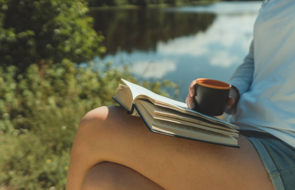 湖のそばのテントで本を読んでいる女. - 写真・画像