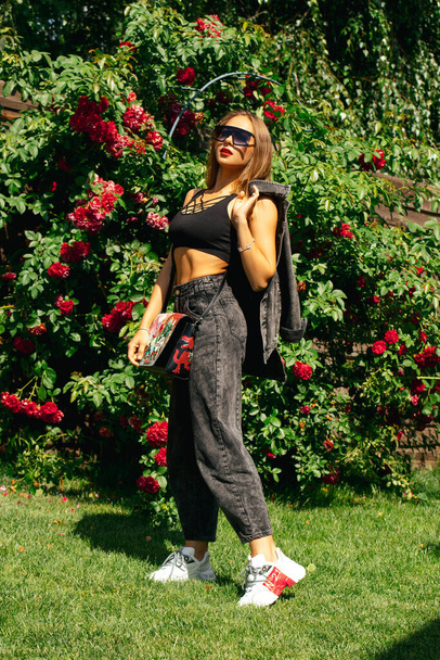  joven hermosa mujer en gafas de sol posando en el jardín
  - Foto, Imagen