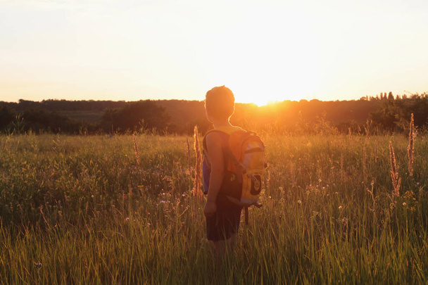   Egy fiú hátizsákkal nézi a naplementét. - Fotó, kép