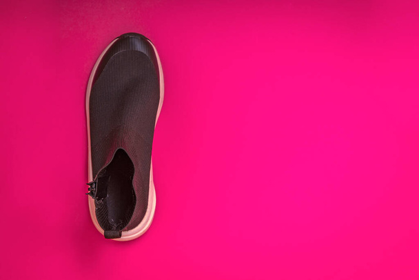 ピンクの背景に美しいファッショナブルな靴下スニーカー。最小限のデザイン。スタイリッシュなブラックスニーカー。トレーニング時間の概念。高解像度画像. - 写真・画像