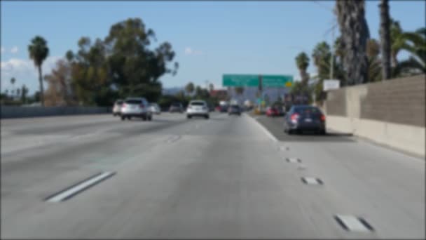 Jazda autostradą międzymiastową w Los Angeles, Kalifornia USA. Nieostry widok z przedniej szyby samochodu na ruchliwej autostradzie międzystanowej. Zamazane przedmieścia wielokrotnego podjazdu. Kamera wewnątrz auto w LA - Materiał filmowy, wideo