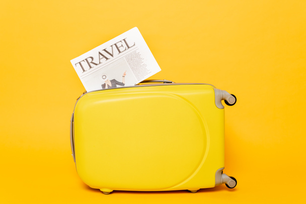 travel newspaper on colorful suitcase on yellow background - Фото, изображение