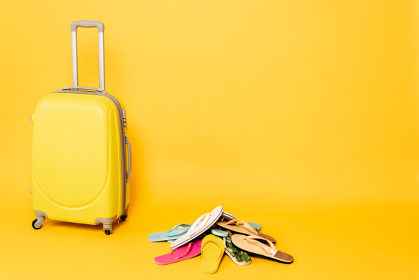 travel bag with colorful flip flops on yellow background - Zdjęcie, obraz