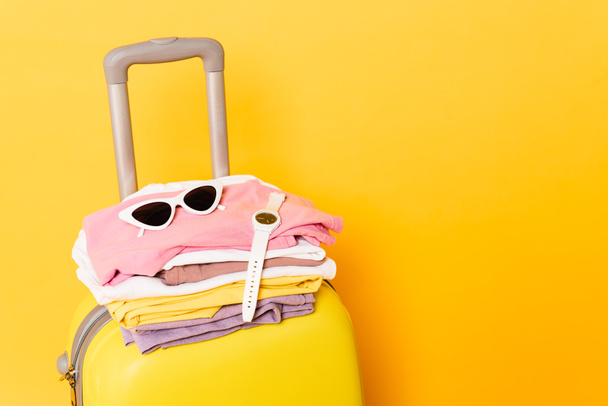 bolsa de viaje con ropa de verano y accesorios sobre fondo amarillo
 - Foto, Imagen