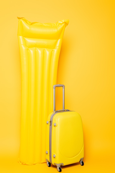 travel bag near pool float on yellow background - Foto, Bild